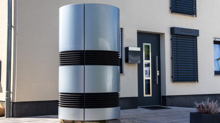 Eine moderne Luft-Wasser-Wärmepumpe vor einem Einfamilienhaus