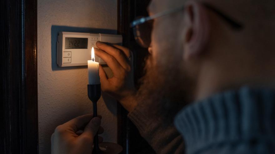 Ein Mann leuchtet bei Stromausfall mit einer Kerze am Sicherungskasten