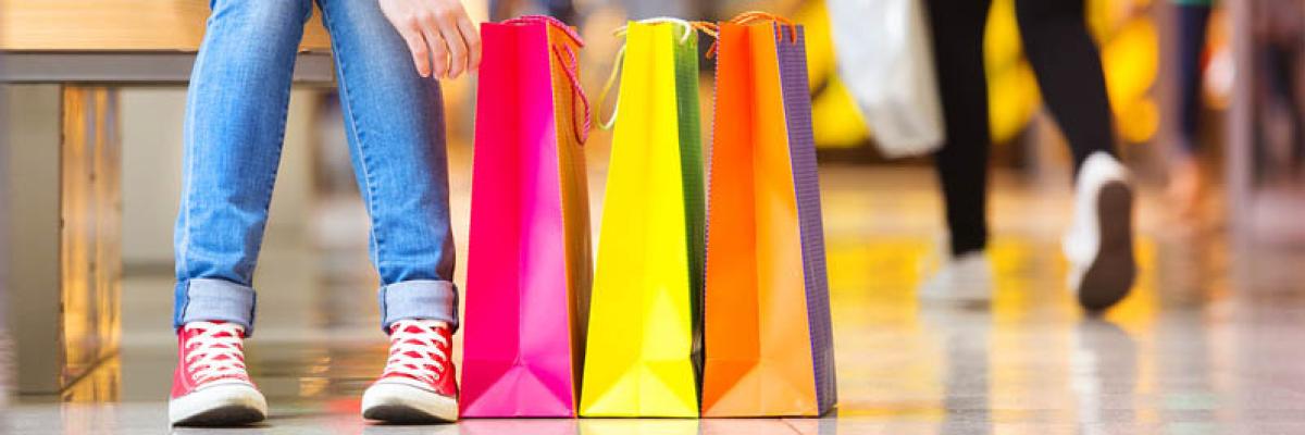 Junge Frau mit Einkaufstüten macht Pause beim Shopping