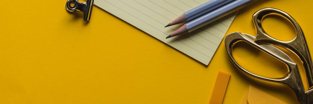 Gelber Schreibtisch mit Schere, Stiften und Papier