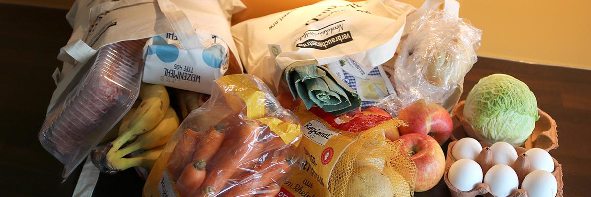 Zwei volle Einkaufsbeutel mit Lebensmitteln liegen auf einer Küchenarbeitsplatte.