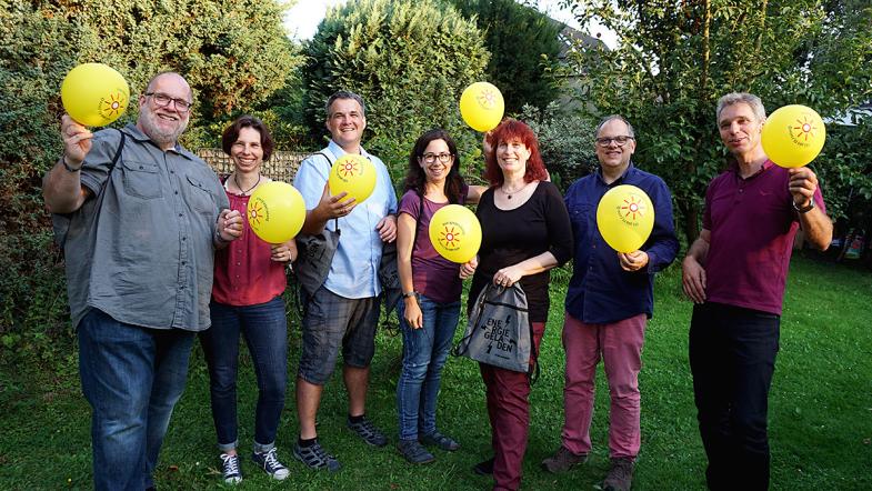 Gäste der Energiesparparty mit Energieberater und Luftballons in der Hand
