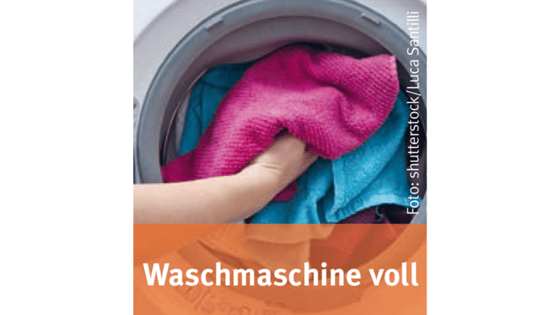 Jemand stopft Wäsche in eine Waschmaschine