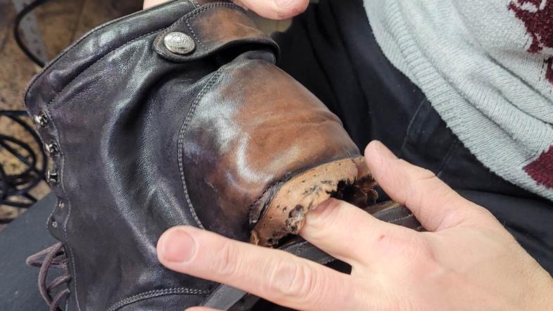 Jemand steckt den Finger in ein Loch in einem Schuh
