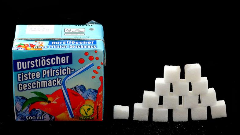 Trinkpackung Durstlöscher und zur Pyramide gestapelte Zuckerwürfel