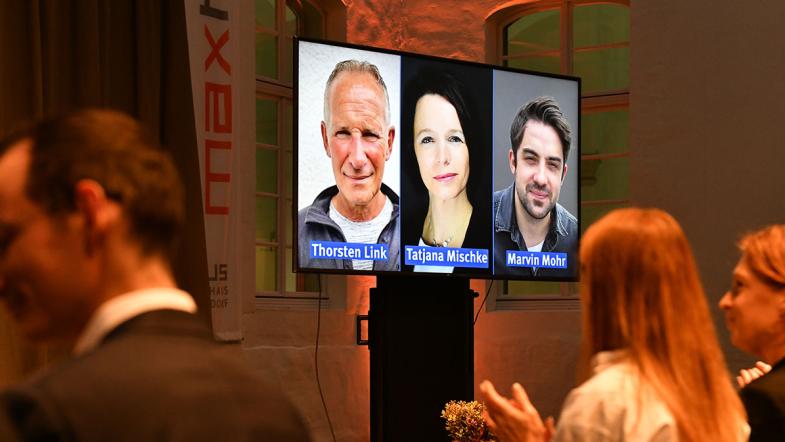 Teilnehmende auf einem Videoscreen