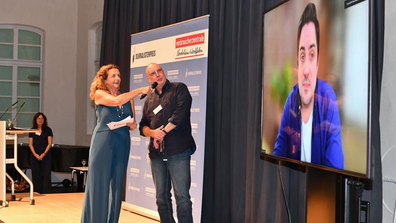 Moderatorin und Jurymitglied und zugeschaltetem Gewinner auf Videoscreen
