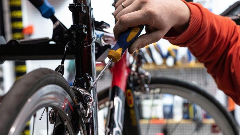 Hand hält Schraubendreher an eine Fahrradbremse