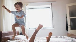 Junge springt über Bett