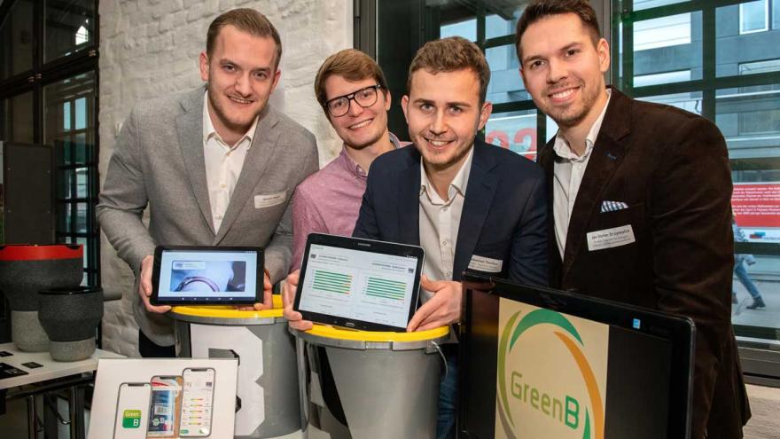 Vier Studenten zeigen auf zwei Tablets eine App