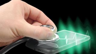 Hand hält Stethoskop auf Smartphone-Display, dazu eine Herzstromkurve