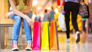 Junge Frau mit Einkaufstüten macht Pause beim Shopping