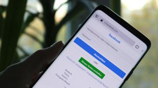 Hand hält Smartphone mit Facebook-Anmeldeseite