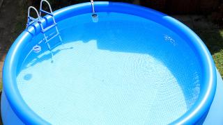Blauer aufblasbarer Pool mit Wasser gefüllt und Leiter im Garten