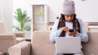 Mann mit Mütze und Schal am Laptop und Handy