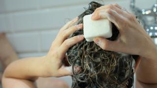 Frau wäscht sich die Haare mit fester Shampooseife