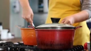 Eine Person steht am Herd und rührt in einem Kochtopf