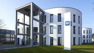 Firmenzentrale der 1&1 Telecom GmbH in Montabaur: Zwei weiße dreistöckige Gebäude und eine weiße Säule mit dem Logo 1&1, weiße Schrift auf blauem Quadrat