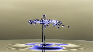 Aufnahme eines farbigen Tropfens, der auf klares Wasser trifft