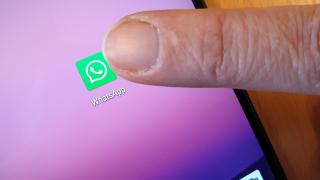 Ein Finger tippt aufs WhatsApp-Logo auf einem Smartphone-Display