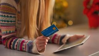 Ein Mädchen hält eine Kreditkarte neben einem Tablet in der Hand