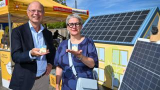 Silke Krebs, Staatssekretärin im Ministerium für Wirtschaft, Industrie, Klimaschutz und Energie des Landes Nordrhein-Westfalen und Wolfgang Schuldzinski, Vorstand der Verbraucherzentrale NRW zeigen kleine Modelle eines Hauses mit einem Stand der Verbraucherzentrale im Hintergrund
