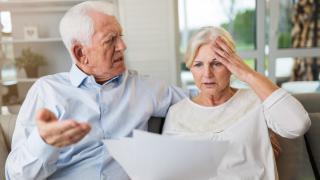 Älteres Ehepaar schaut entsetzt auf Dokumente