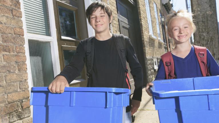 Kinder mit blauen Recyclingtonnen